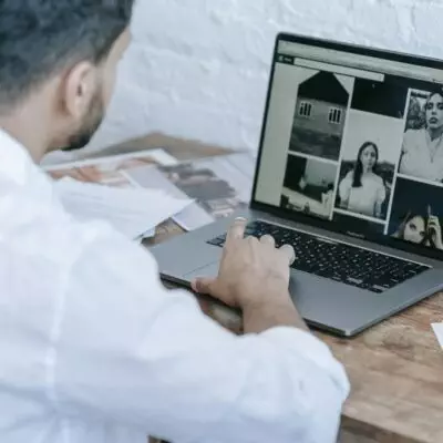 Side view of crop bearded male photographer using laptop while preparing pictures for publishing in modern workplace